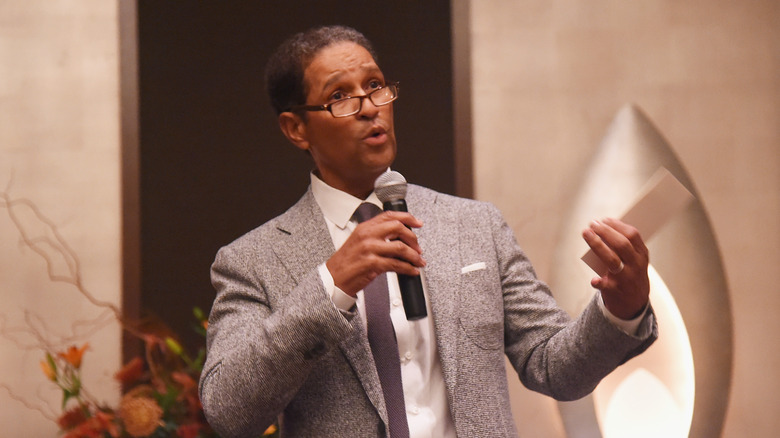 Bryant Gumbel suit glasses holding mic talking