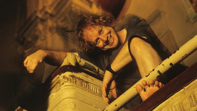 Danny Elfman crouching on a balcony
