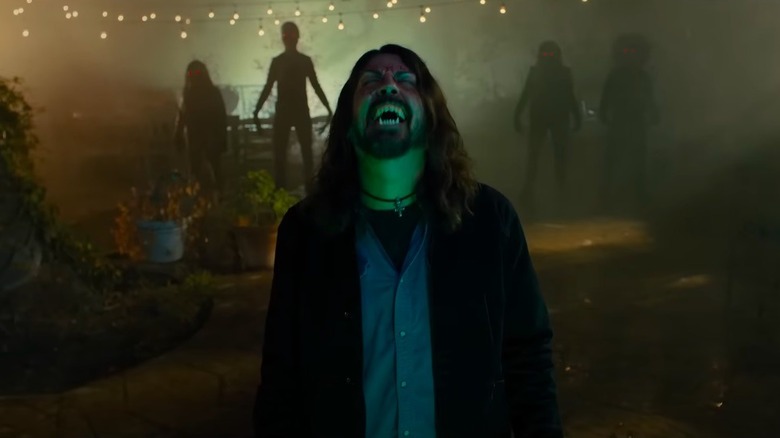 Dave Grohl face upturned with fangs and zombies in scene from Studio 666