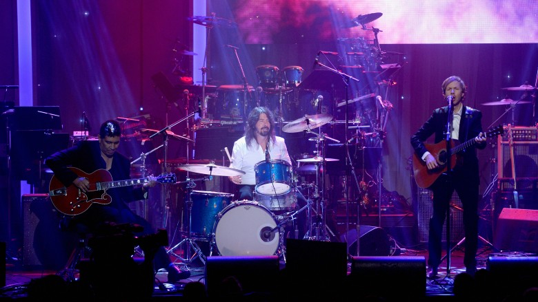 Dave Grohl drumming in white suit on stage
