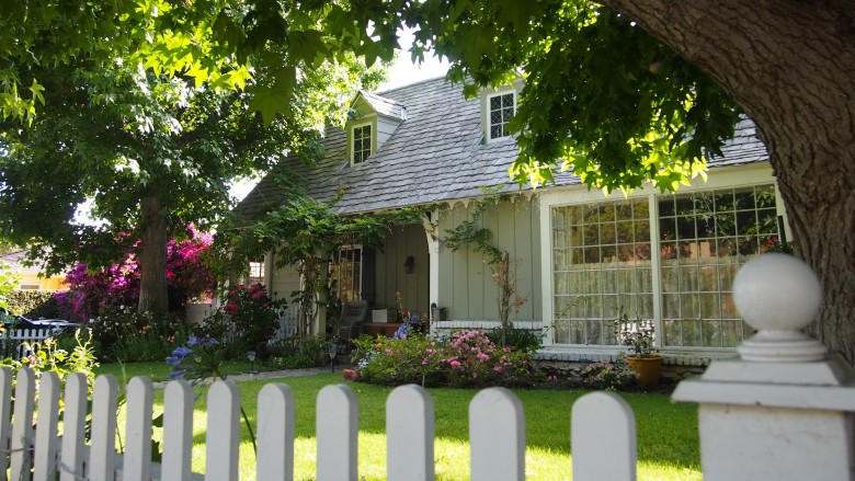 Exterior view of sunlit garden in front of a white house