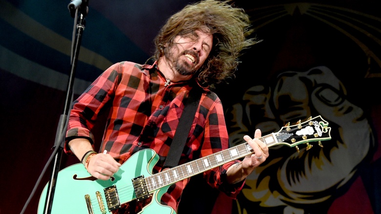 Dave Grohl in a flannel shirt playing guitar on stage.
