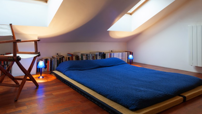 Blue futon on hardwood flooring in attic bedroom