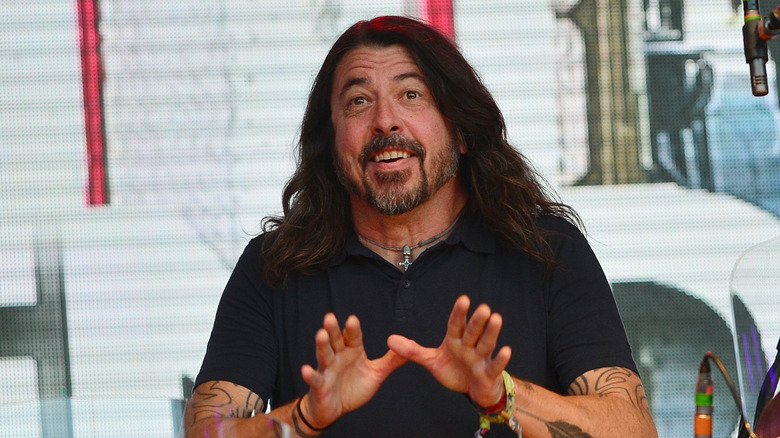 Dave Grohl smiling in black shirt sitting at drums onstage