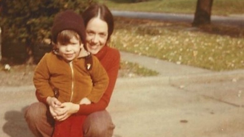 Dave Grohl as a child smiling being held by his smiling mom outdoors