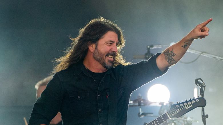 Dave Grohl in black shirt smiling and pointing on stage