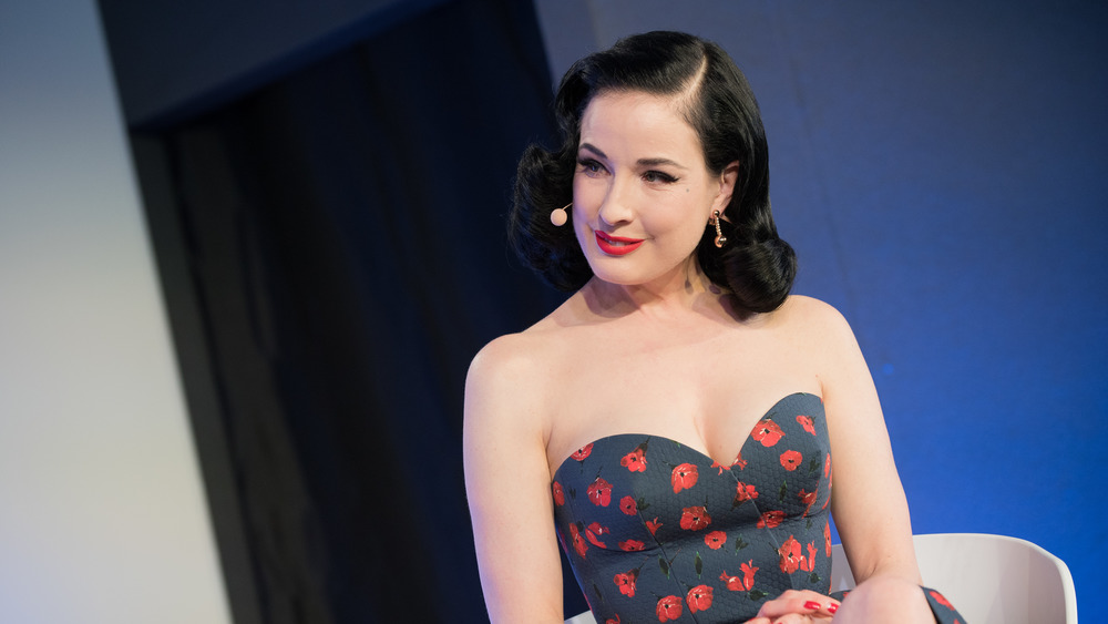 Dita von Teese sitting with a head mic, listening to another speaker
