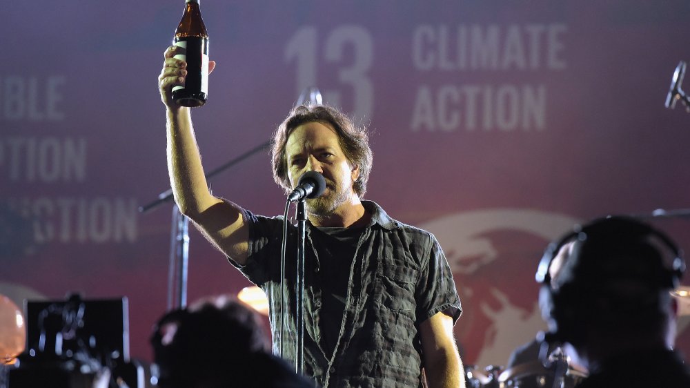 Eddie Vedder on stage mic holding up beer bottle