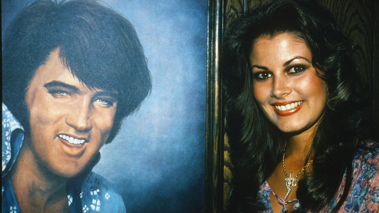 Ginger Alden posing next to a portrait of Elvis Presley in 1978