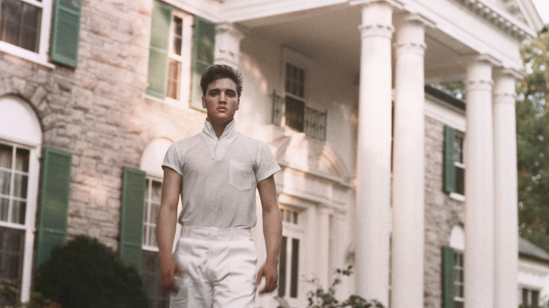 Elvis standing afront façade of Graceland