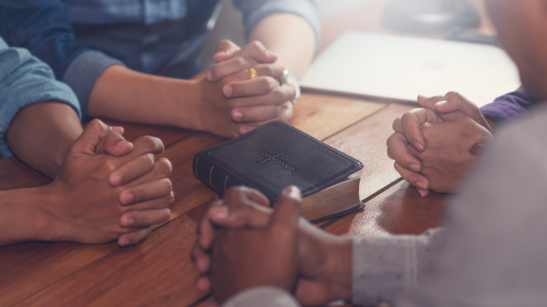 praying hands around a Bible