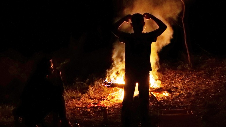 Two people silhouetted by fire