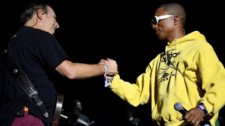 Hans Zimmer and Pharrell hold hands on stage