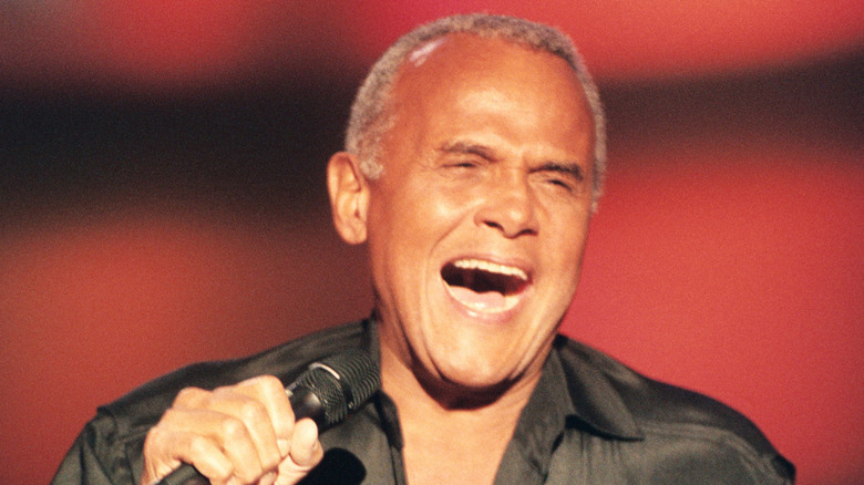 Harry Belafonte singing into a microphone onstage