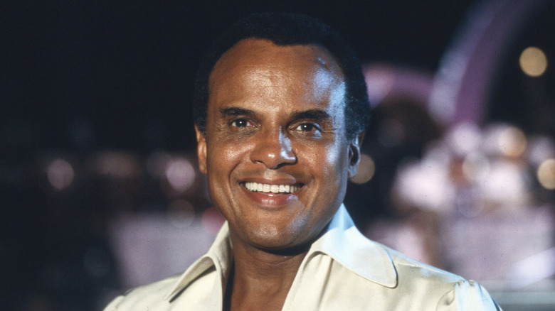 A young Harry Belafonte smiling with lights in the background