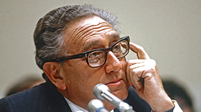 Henry Kissinger with finger on head