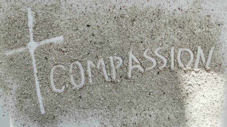 compassion with cross written in the sand