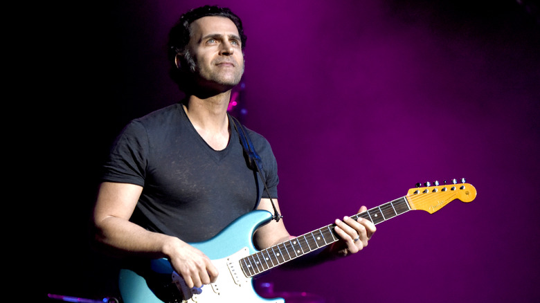 Dweezil Zappa holding a guitar onstage