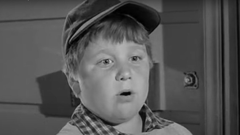 Rusty Stevens as Larry Mondello wearing hat