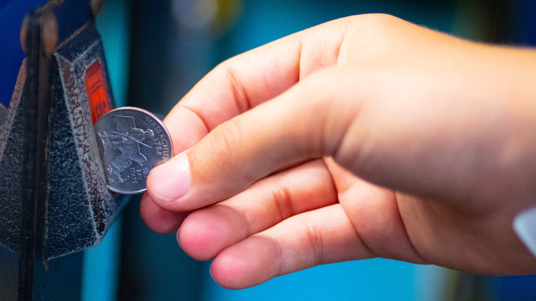 child hand inserting quarter arcade game