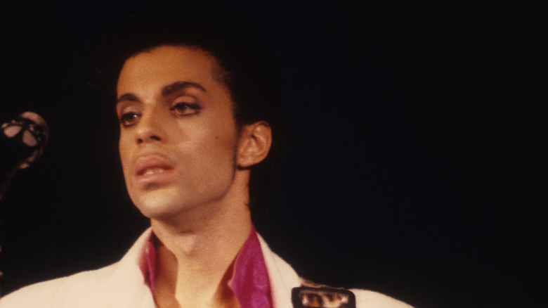 Prince performing in white suit with guitar