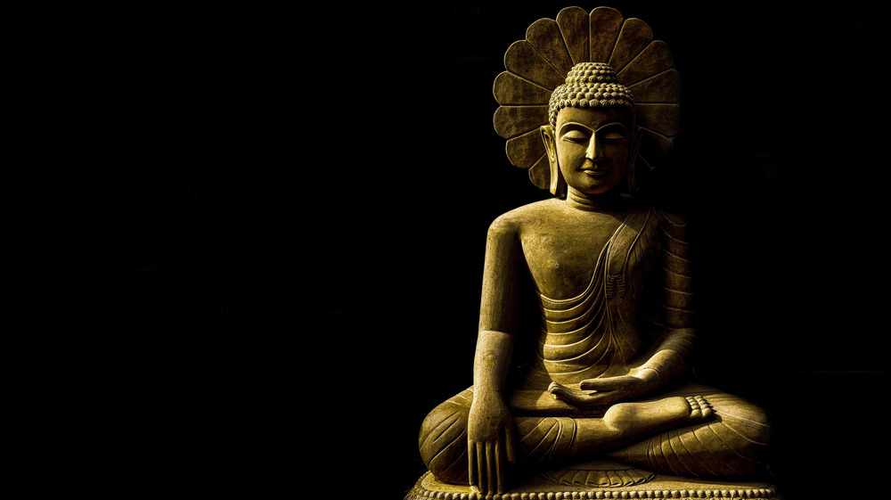 Buddha meditating against dark background