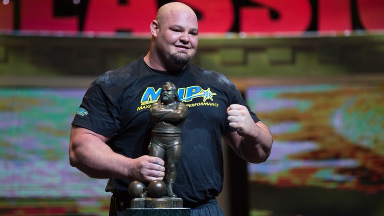 Brian Shaw holding a trophy on stage
