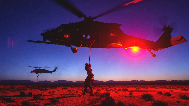 Airmen repelling from helicopter in desert
