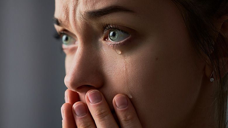 A woman crying with hands over mouth