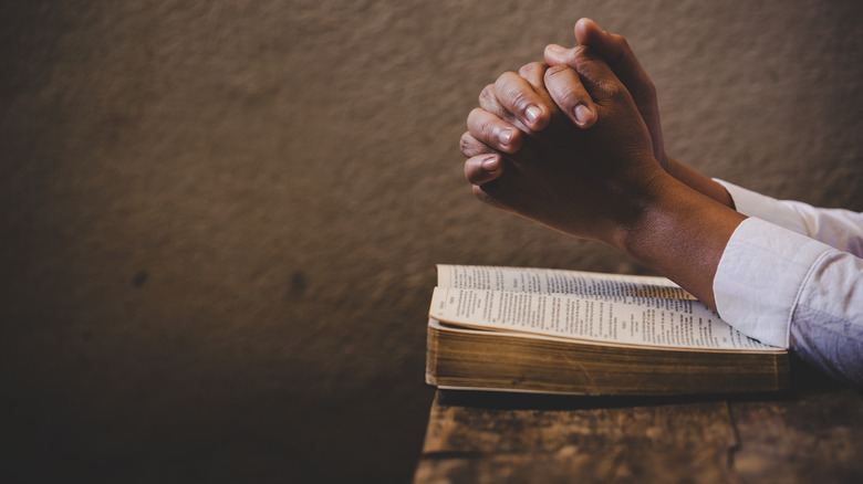 folded hands on a bible
