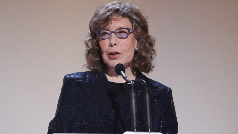 Lily Tomlin wearing glasses and speaking on stage in 2023