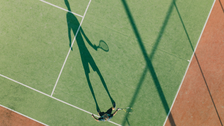 Overhead view of tennis player casting long shadow