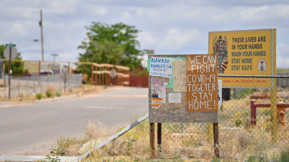 A community bulletin board and a sign with a message about staying safe from the coronavirus are posted at the entrance to the East To'hajiilee housing community