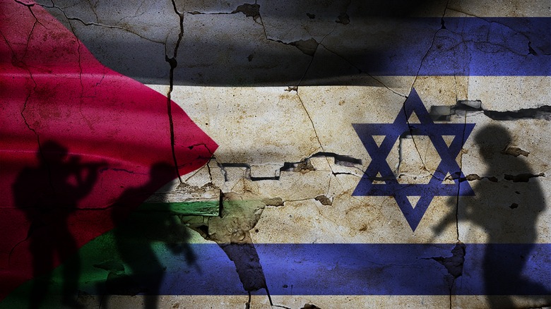 soldiers against a wall painted with Israel and Palestine flags