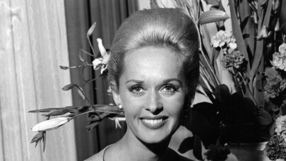 Tippi Hedren smiling in front of flowers