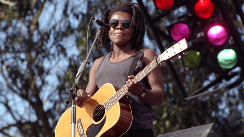 Tracy Chapman on stage with guitar and sunglasses