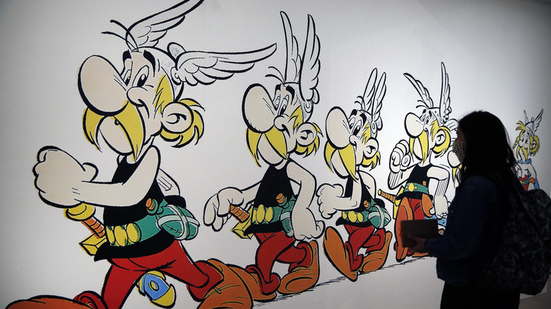 A visitor wearing a protective mask looks at a drawing representing the character of Asterix by French designer Uderzo