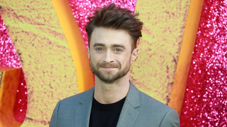Daniel Radcliffe is at a premiere with a colorful backdrop.