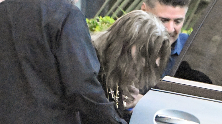 Ozzy Osbourne being helped into a car