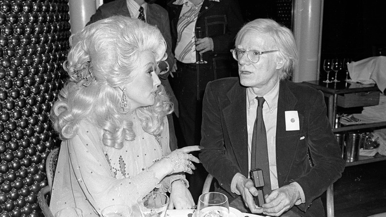 Dolly Parton and Andy Warhol sit together at Windows on the World restaurant, 1977