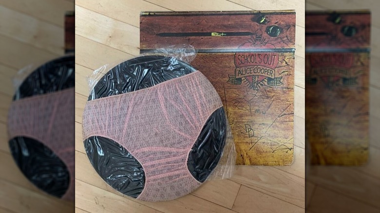 Alice Cooper's "School's Out" album with the underwear-wrapped record, set on a wooden floor