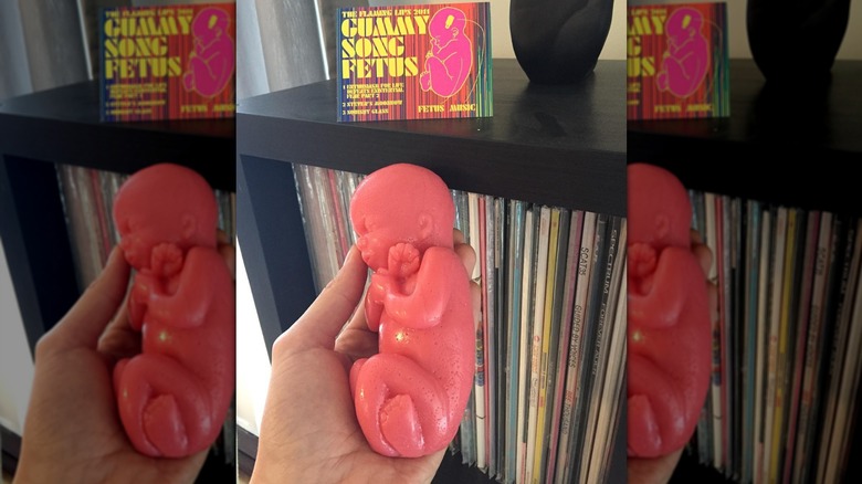 A hand holding Flaming Lips' "Gummy Song Fetus," a fetus made out of gummy candy