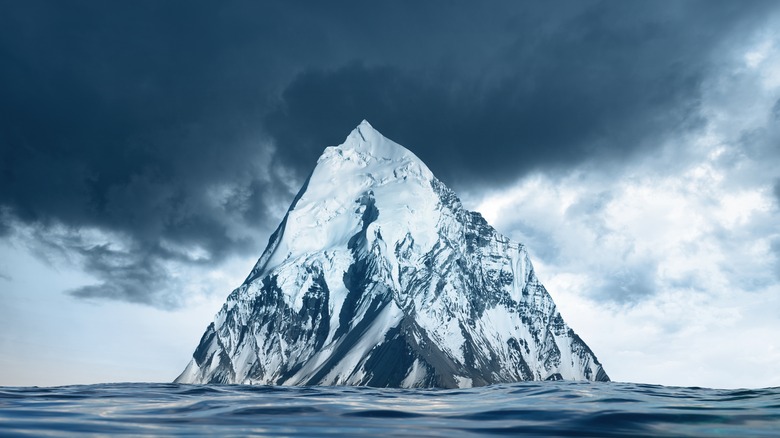 Iceberg resembling mountain emerging from surface of water