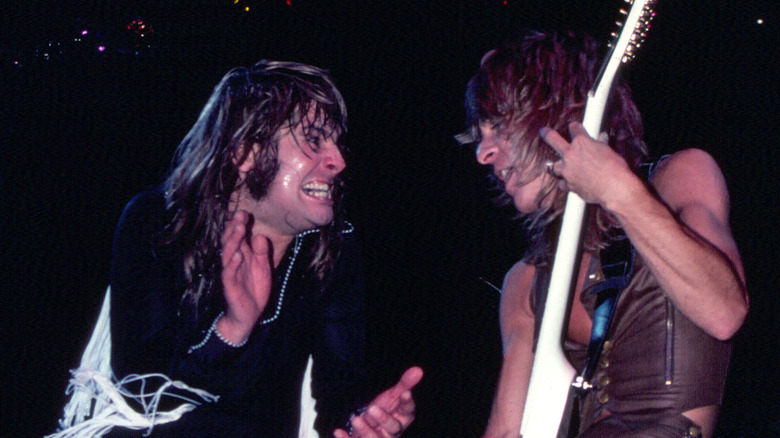 Ozzy Osbourne smiling as Randy Rhoads plays guitar