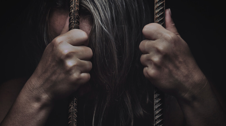 woman behind rusted bars