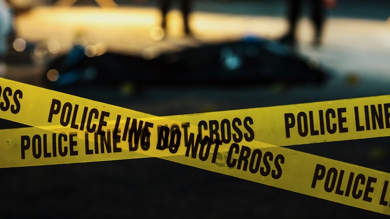 Police tape with detectives working in background