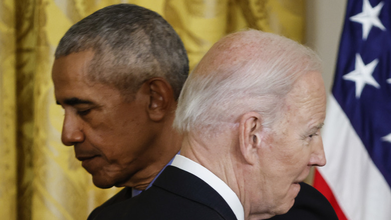 Barck Obama and Joe Biden embracing with somber looks