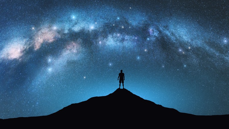 person on hill with starry skies