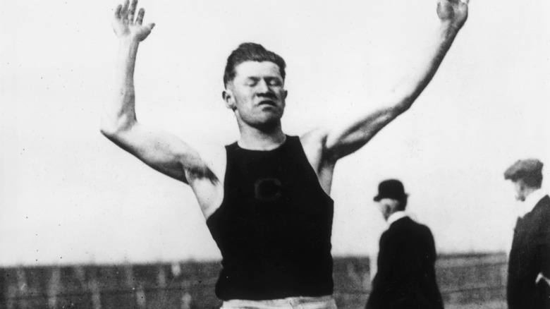 Jim Thorpe with arms outstretched doing track event at 1912 Olympic trials