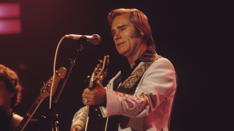 George Jones playing a guitar on stage